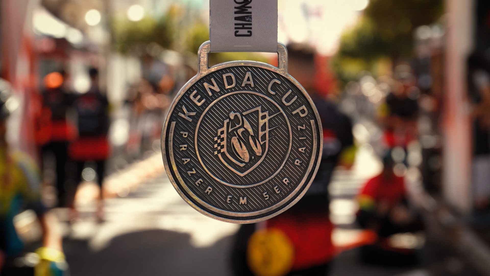 Close-up of a KendaCup medal with the event softly blurred behind it